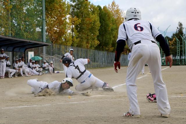 甲斐Aの選手がホームベースに滑りこんで点を挙げている写真