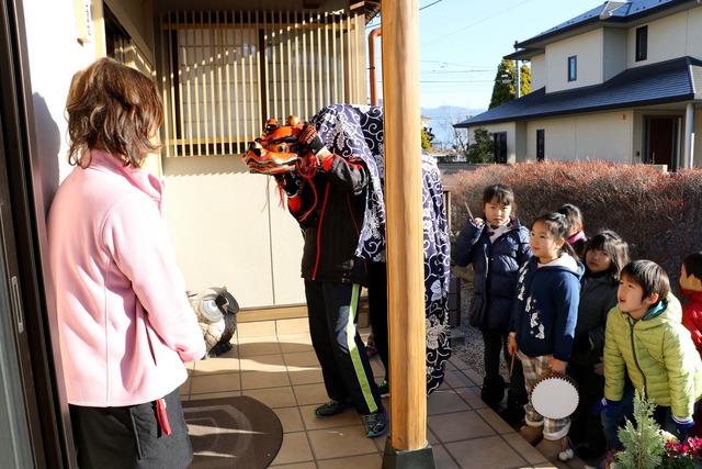 獅子舞と太鼓を持った子ども達が家の玄関の前に立っている写真