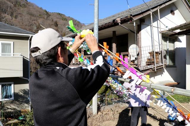 区民が竹の枝飾りを仕上げていっている写真