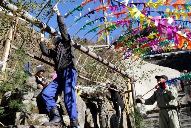 竹の枝飾りを道祖神に飾り付けている写真