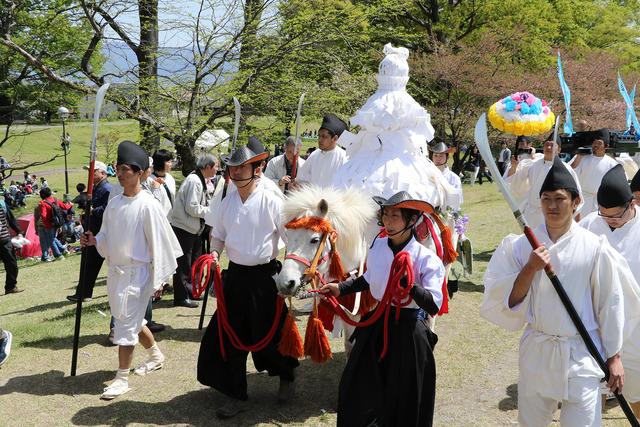 白い神馬に運ばれる三宮の「ぼんぼこさん」と、神馬をひく2人の男女と、その両脇を白装束の複数の男性が歩く写真