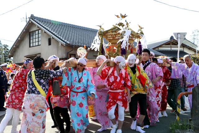 ピンク、赤、黄色といった鮮やかな浴衣を着て女装した男性が竜王神輿を担いでいる写真