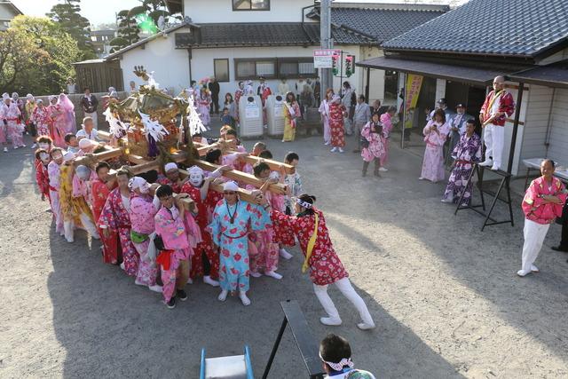 浴衣を着て女装した男性が担いでいる竜王神輿が公会堂に到着した写真