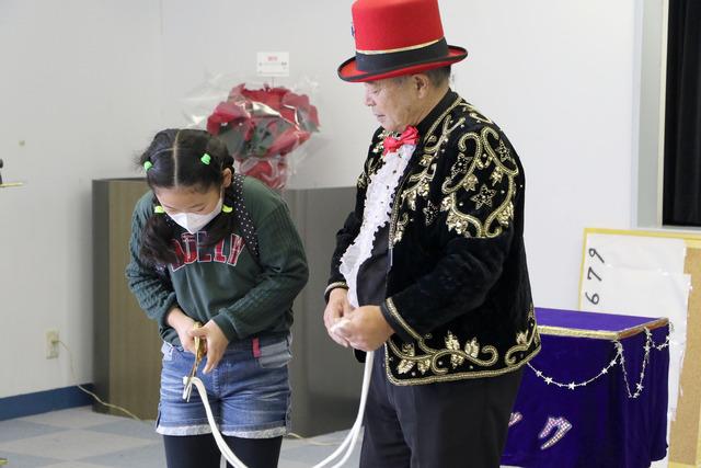 ミスターマジックリン鷹野さんと、はさみを持った女の子がロープを切ろうとしている写真