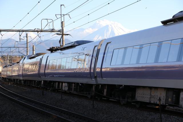 富士山を背景に走行する白い車体に紫のラインが入った「E351系スーパーあずさ号」の写真