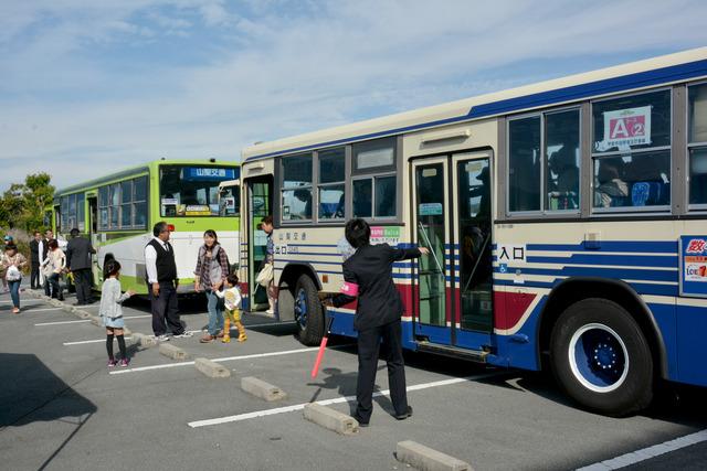 駐車場に止まったシャトルバスから参加者が下りてくる写真