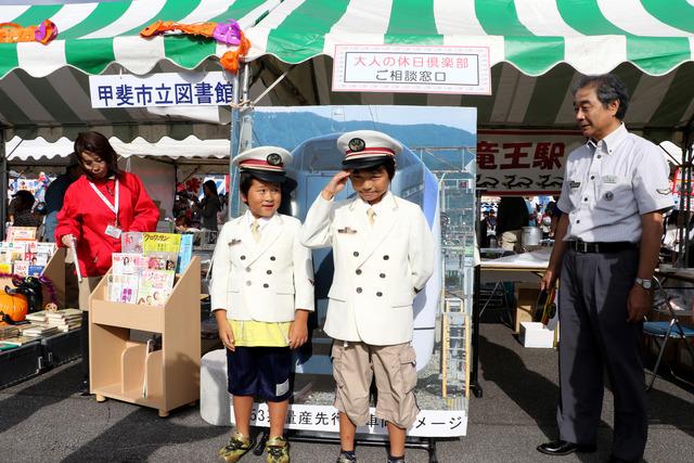 JR東日本竜王駅のブースの前で制服を着た2人の男の子が記念撮影している写真