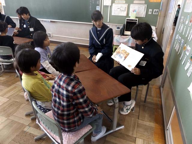 中学生が小学生に絵本を読んでいる写真