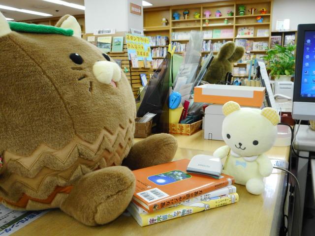 ぬいぐるみが図書館で本の貸し出しをしている様子の写真