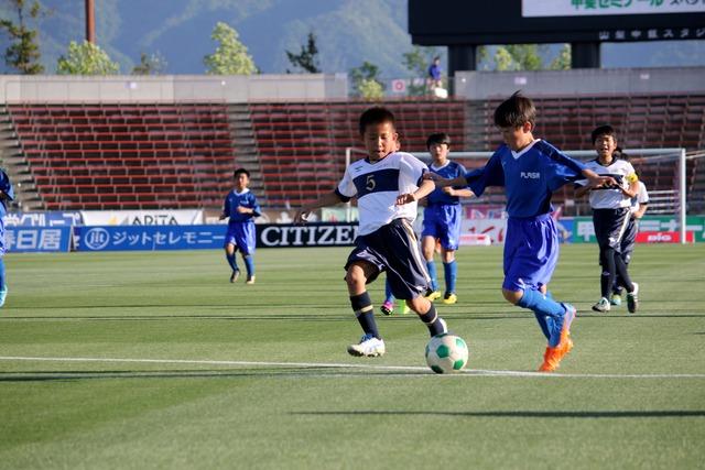 ピッチ内で真剣にサッカーをする子供たちの写真