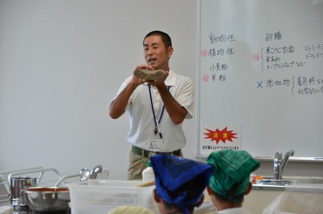 市生涯学習文化課の長谷川文化財主事が石を持ちながら参加者に説明をしている写真