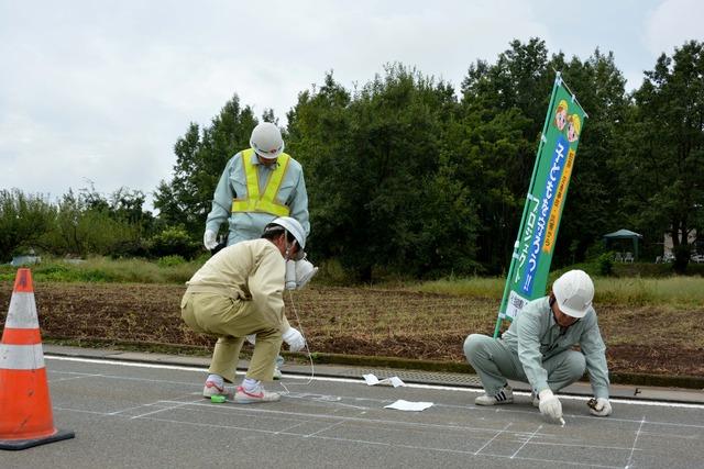 3人の作業員が地面に白い線を引いている写真