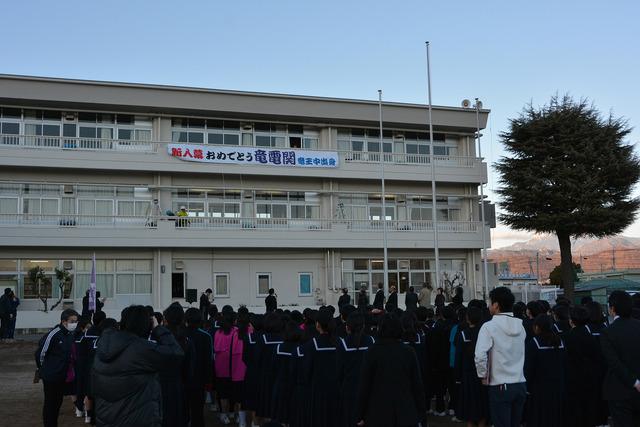 校舎に掲げられた横断幕を見上げる生徒達の写真