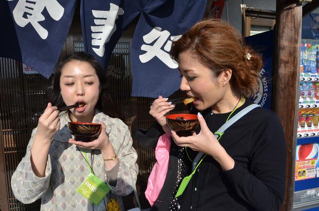 お椀を持って、大根を食べる女性二人の写真