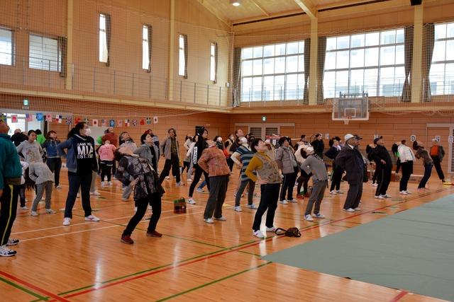 体育館で体操をするたくさんの人々の写真