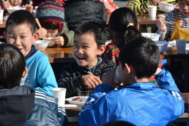 子どもたちがつきたての餅と温かい芋煮汁を楽しそうに食べている写真