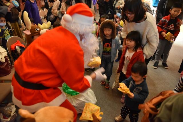 サンタクロースが子供たちにプレゼントを手渡ししている様子の写真