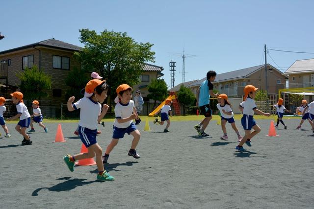 帽子をかぶった園児たちが走り回っている写真