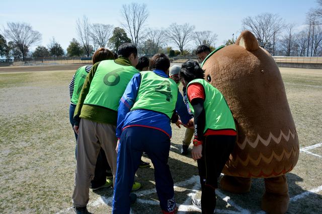 円陣を組むやはたいぬと選手たちの写真