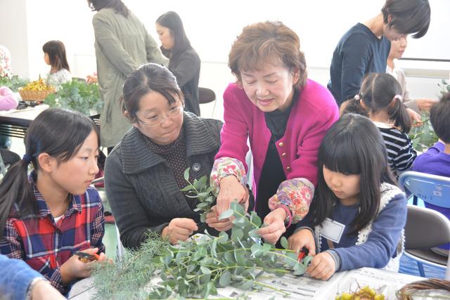講師の女性が受講している親子に植物を手に取りながら教えている写真