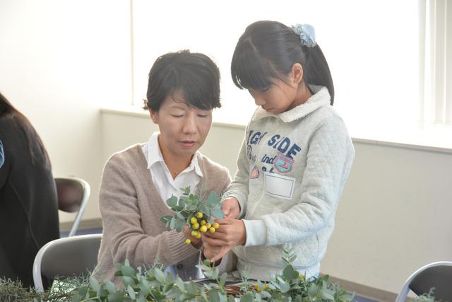 親子で植物を手に取り、リースを製作している写真