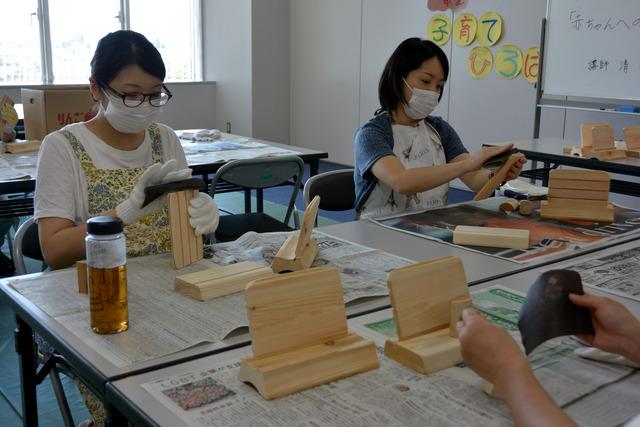 参加者の女性が木の表面を紙やすりで磨いている写真