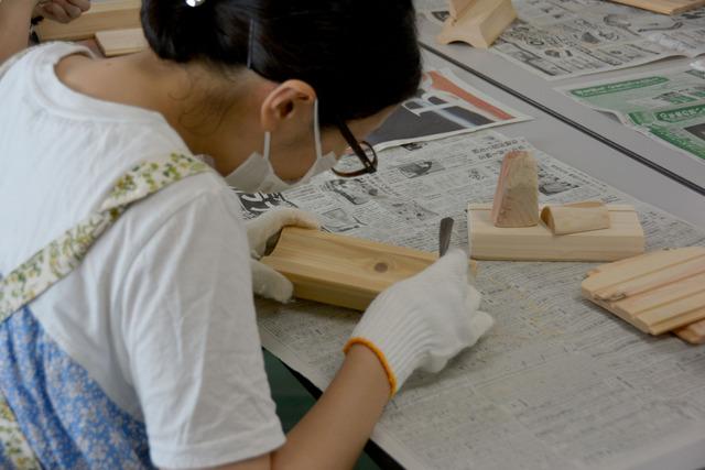 参加者の女性が木の細かい部分まで紙やすりで磨いている写真