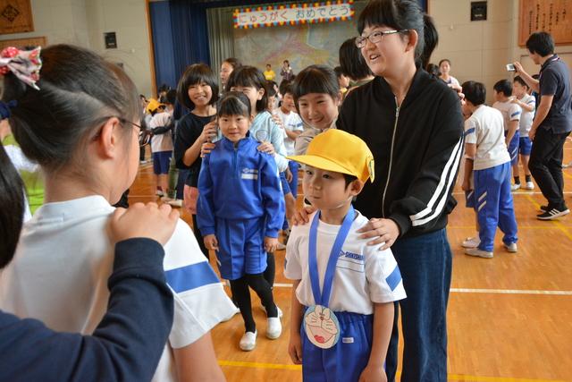 新1年生の後ろに人が連なり、先頭の新1年生がにらめっこをしている写真