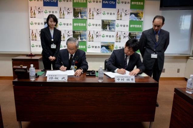 (写真)協定書に調印する株式会社中村建設の関係者と甲斐市長