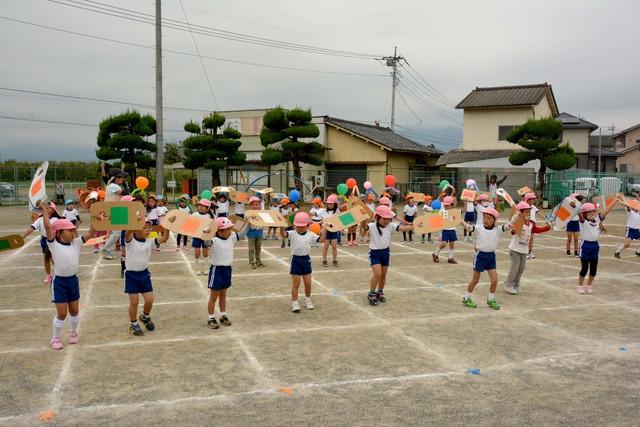 ダンボールで作った道具を持って体操する園児たちの写真