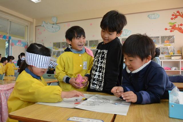 福笑いで遊ぶ児童と園児の写真