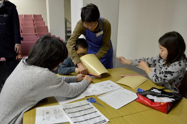 男のが司書に手伝ってもらいながら本にカバーをかけている写真