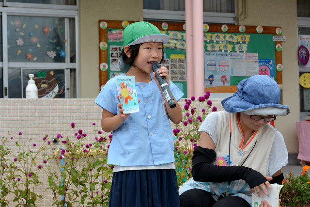 右手にはがきを持ち左手にマイクを持って、作品の発表をする女の子の写真