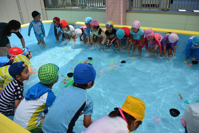 プールで遊ぶ前に、水慣らしする様子の園児たちの写真