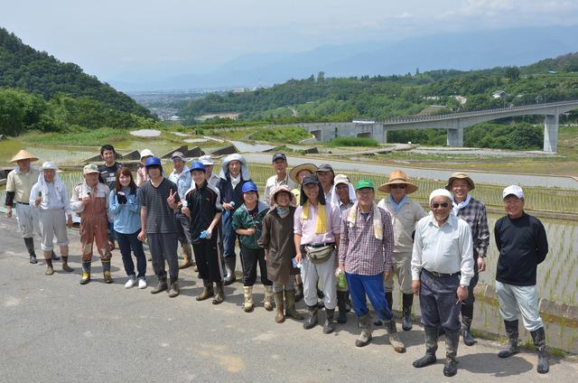 (写真)田園を背景に記念撮影をする参加者たち