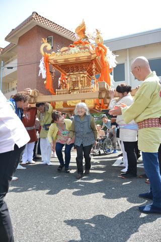 笑顔で、神輿の下をくぐる高齢者の写真