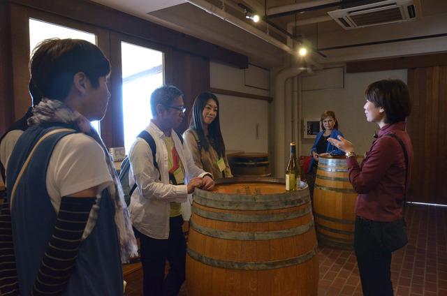 ワイン樽の前で、ぶどうについて学んでいる参加者たち
