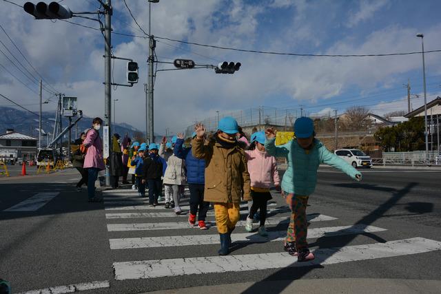 園児たちが手を挙げて横断歩道を渡っている写真