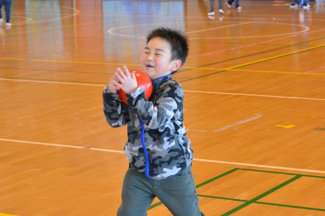 体育館で嬉しそうに赤いボールをキャッチする児童の写真