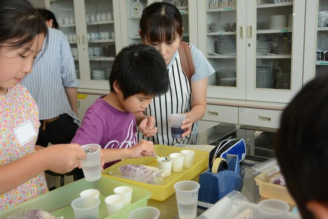 竜王北部公民館で行われた子どもふれあい講座「キッチンで科学しよう」で実験中の小学生たちと保護者たちの写真