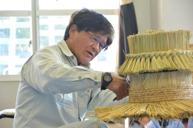 小澤さんが藁をまっすぐに刈り込んでいる写真