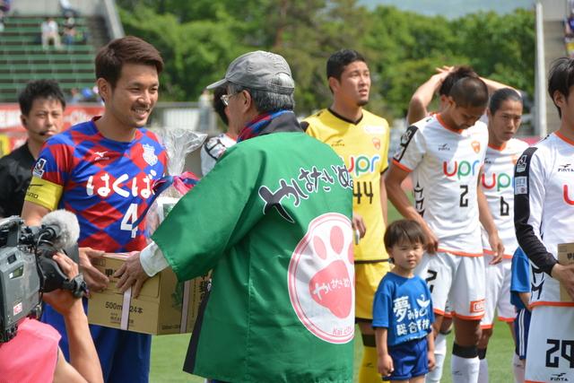 試合前に、甲斐市長が選手たちに特産品の贈呈をしている様子の写真