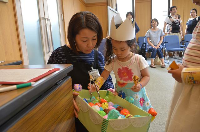 竜王図書館にて折り紙の工作で作られた沢山のボールをトングで挟もうとしている子供の写真