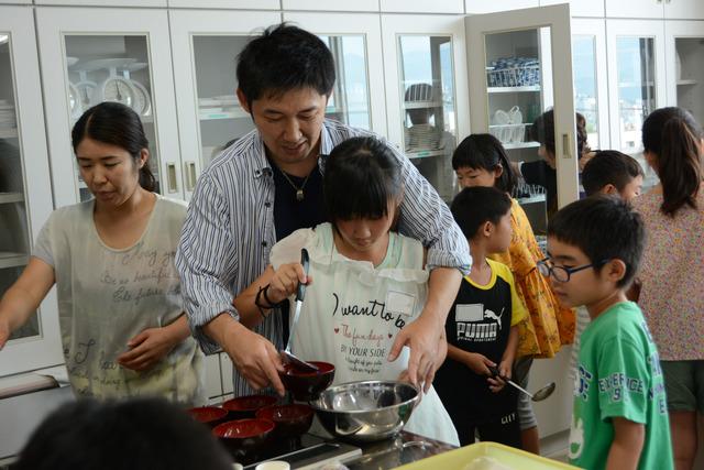 講座「キッチンで科学しよう」にて着色したゼリーを椀によそっている親子の写真