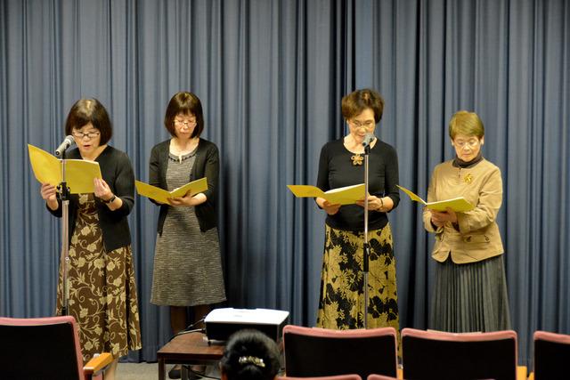 4人の女性がマイクの前に立って朗読している写真