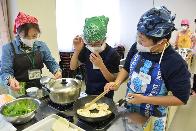 フライパンでピザを焼いている子どもたちの写真