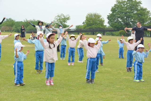 赤坂台総合公園（ドラゴンパーク）で竜王幼稚園の園児たちが大きく手を広げて「甲州弁ラジオ体操」をしている写真