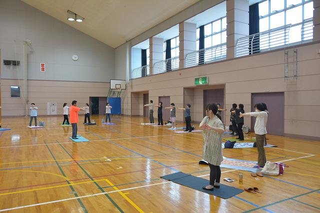 敷島体育館で手を伸ばして、ゆがみ直し整体体操を行う参加者の写真