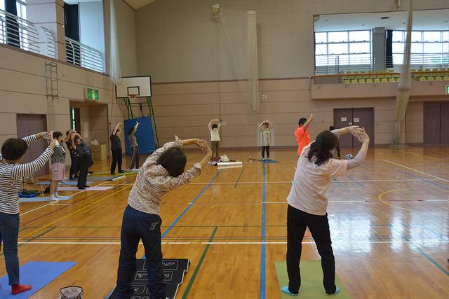 敷島体育館で手を上に組み、ゆがみ直し整体体操を行う参加者の写真