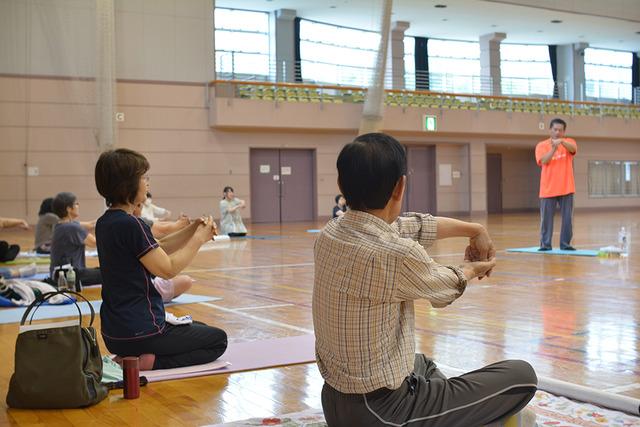 敷島体育館で手を前に出して、ゆがみ直し整体体操を行う参加者の写真